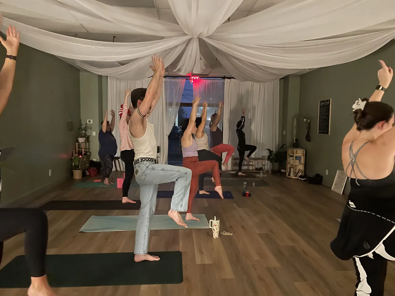 Students reaching up in a standing pose during an evening class.
