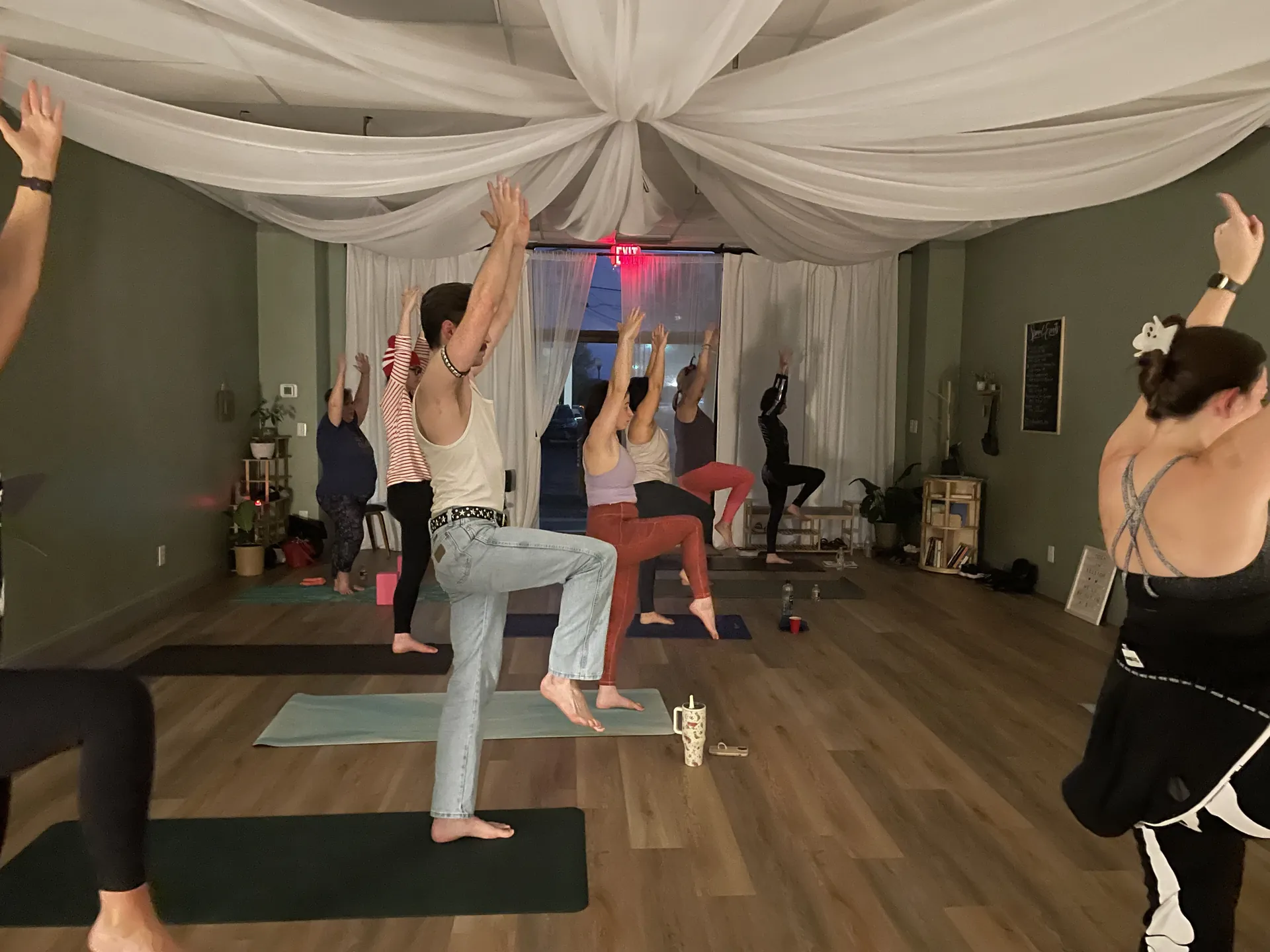 Students reaching up in a standing pose during an evening class.
