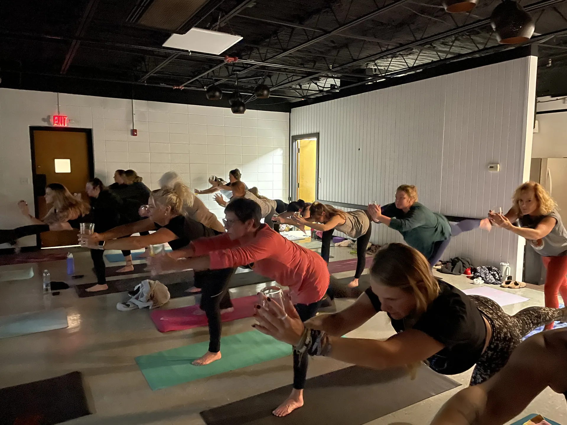 A full room in a wide-legged forward fold at an off-site community class.
