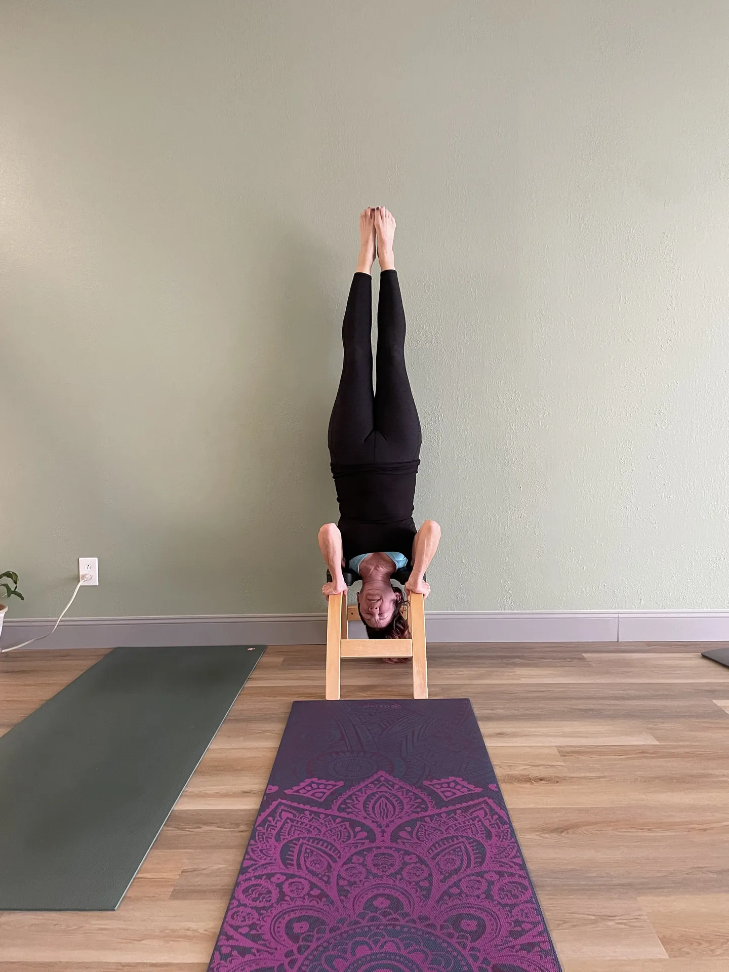 A supported headstand on a headstand bench in the studio.