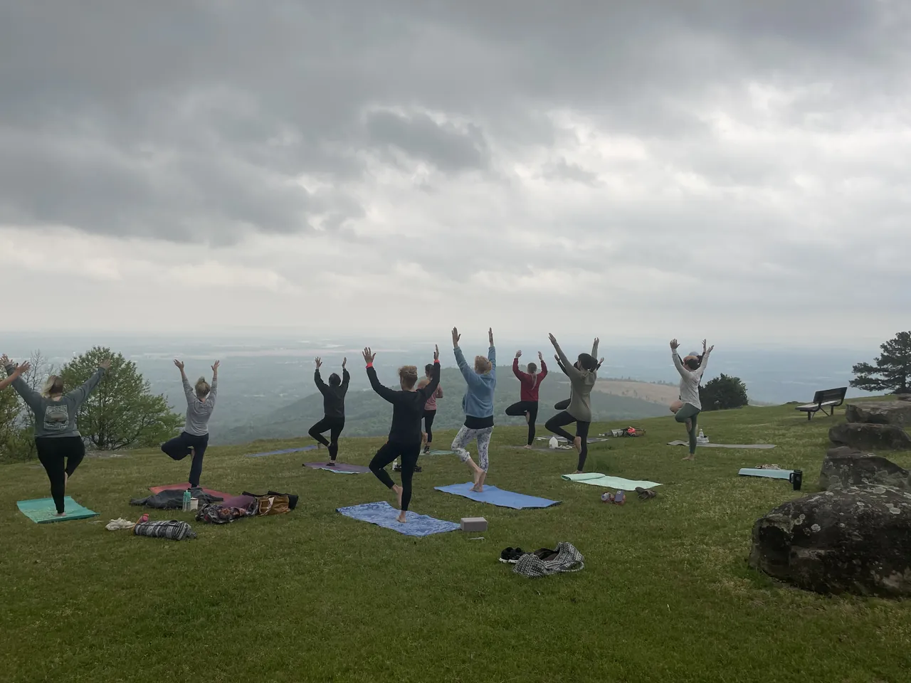 A group in tree pose at Sunrise Point on Mount Nebo, the valley spread out behind them.