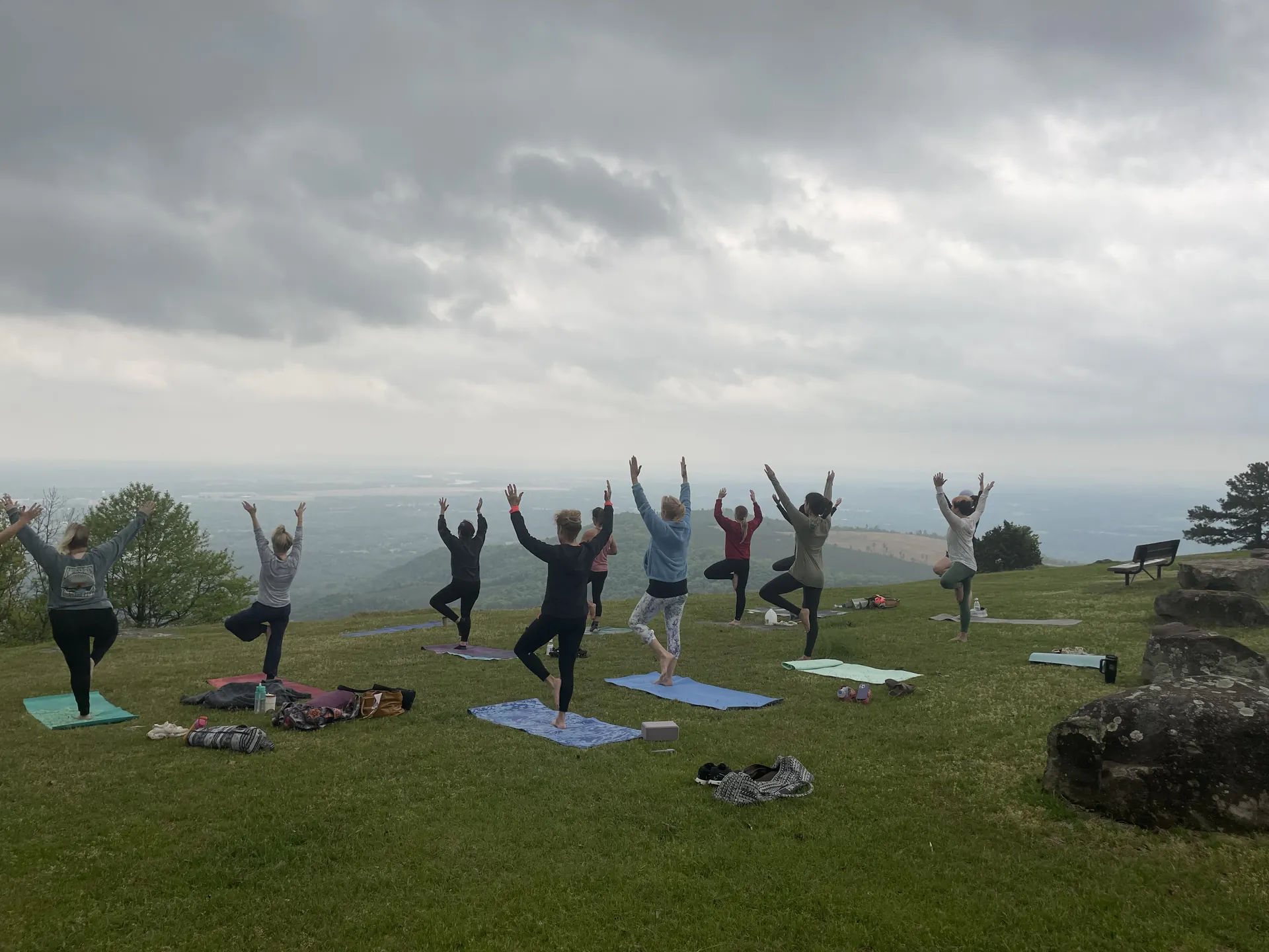 A group in tree pose at Sunrise Point on Mount Nebo, the valley spread out behind them.