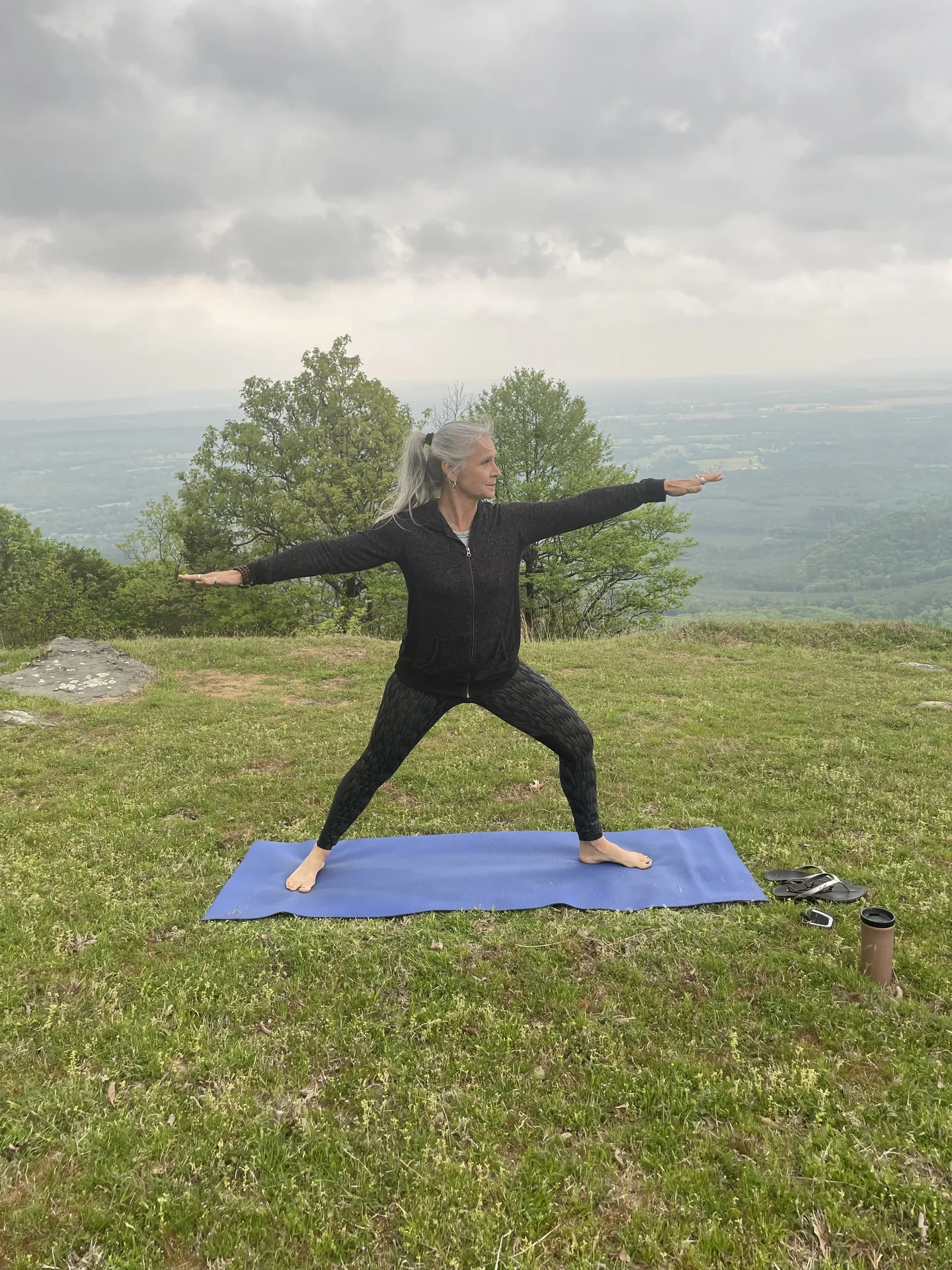 Jill in warrior two on a blue mat at the mountain overlook.