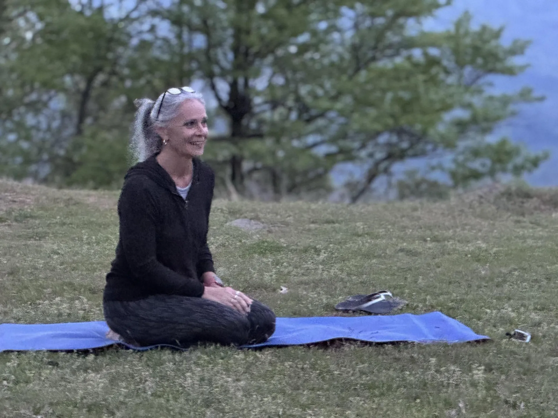 Jill seated on her mat on the mountainside, smiling.