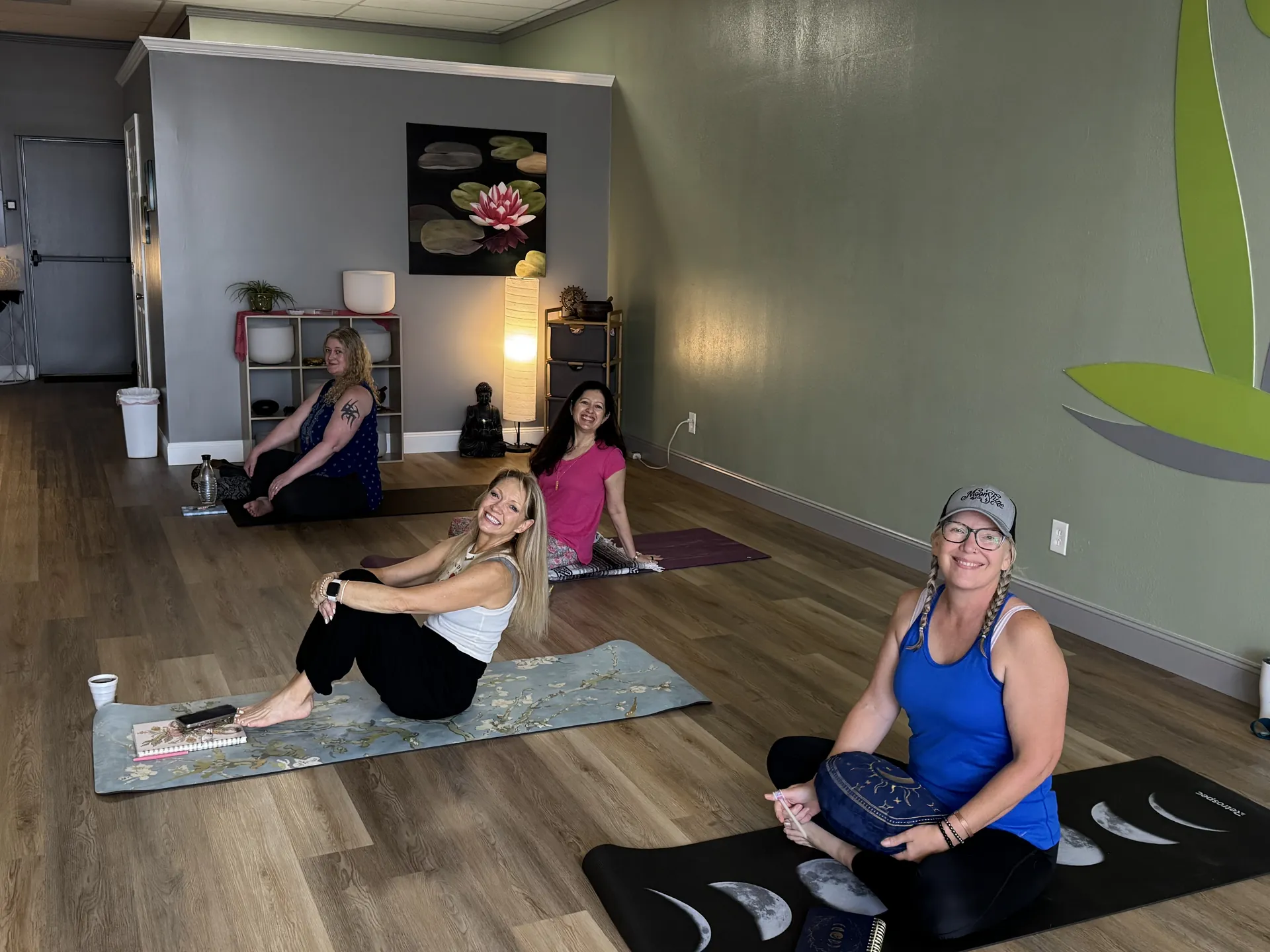 A small group seated on mats in the studio before class.