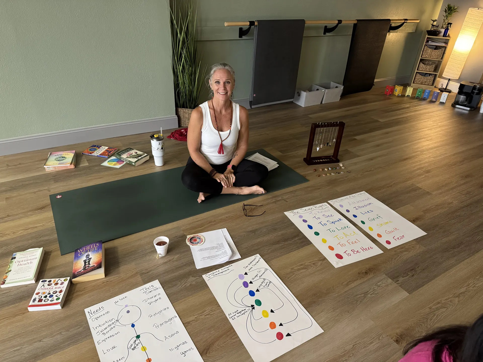 Jill leading a chakra workshop, seated beside hand-drawn charts and books.
