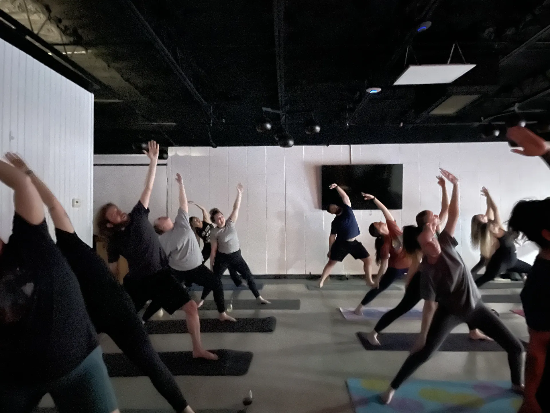 A full room of students in warrior pose at an off-site community class.