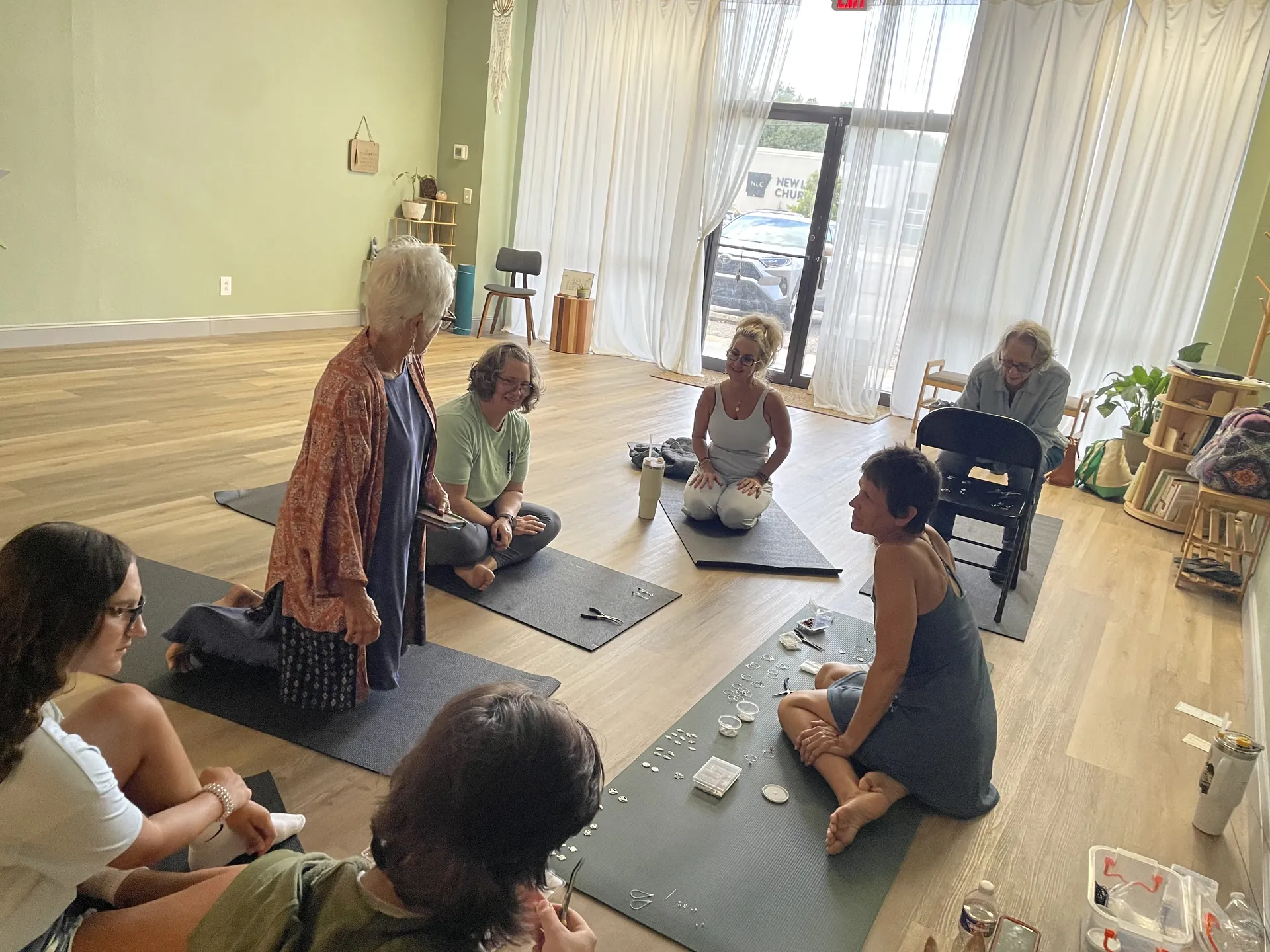 A seated discussion circle during a workshop, morning light through the studio windows.