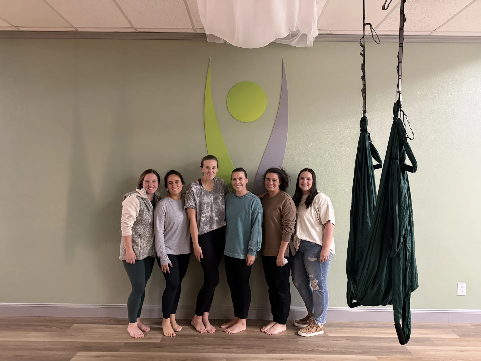 Students gathered by the yoga trapeze in front of the logo mural.