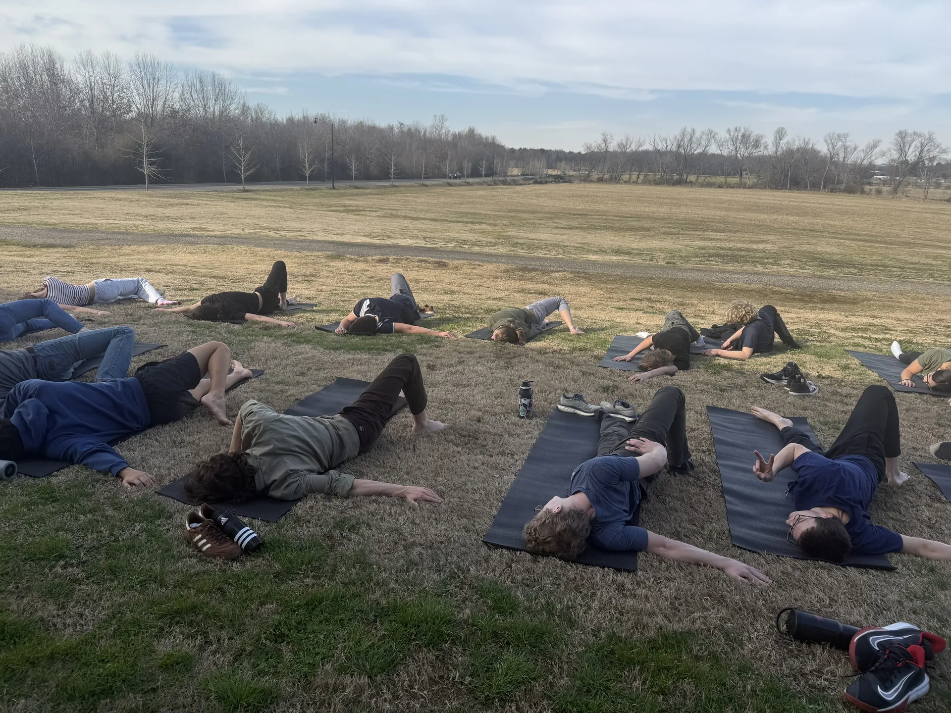 Savasana on the grass at an outdoor evening practice.