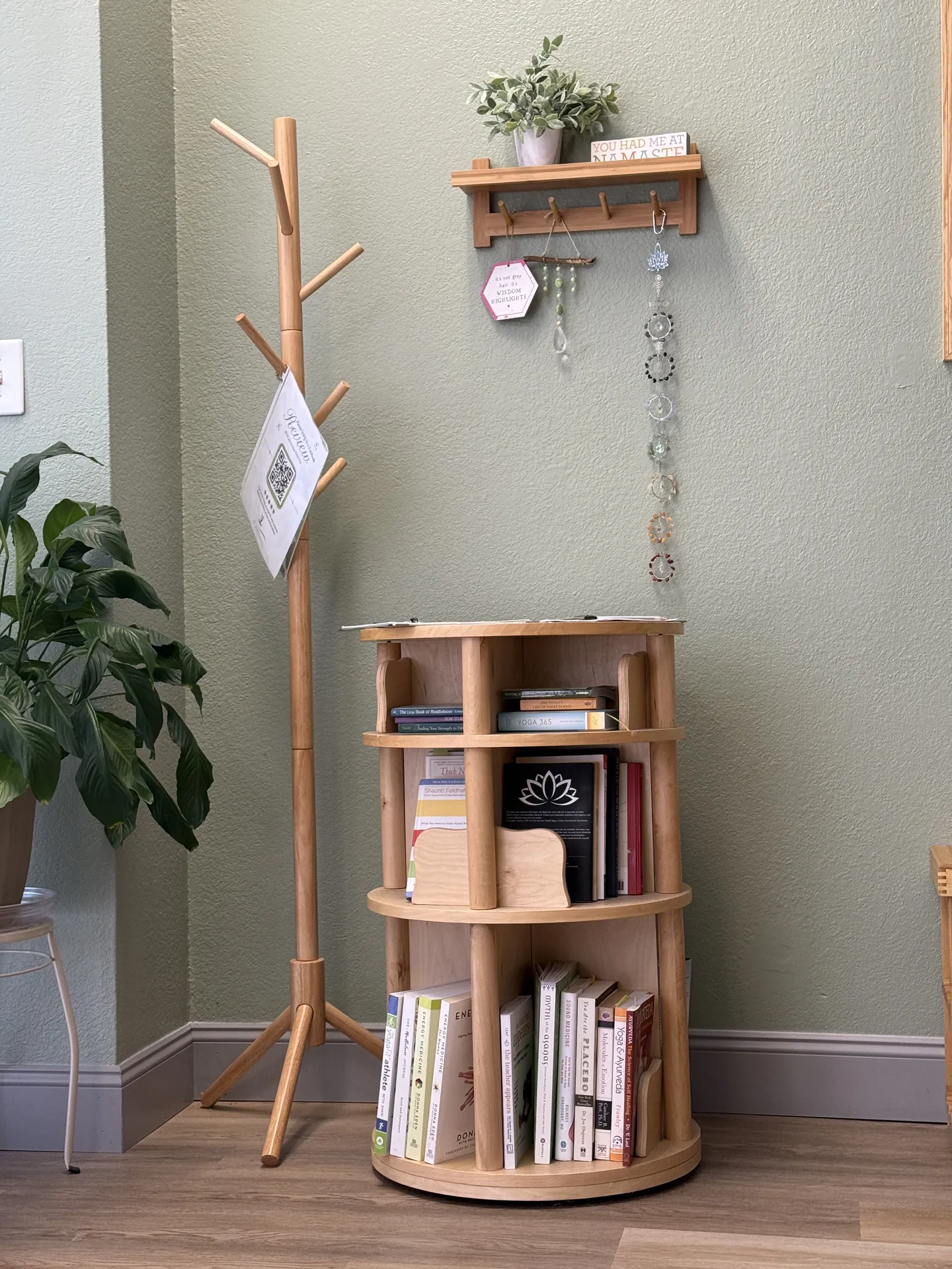 The lending library: a small rotating bookshelf of yoga and wellness books beside a wooden coat stand.