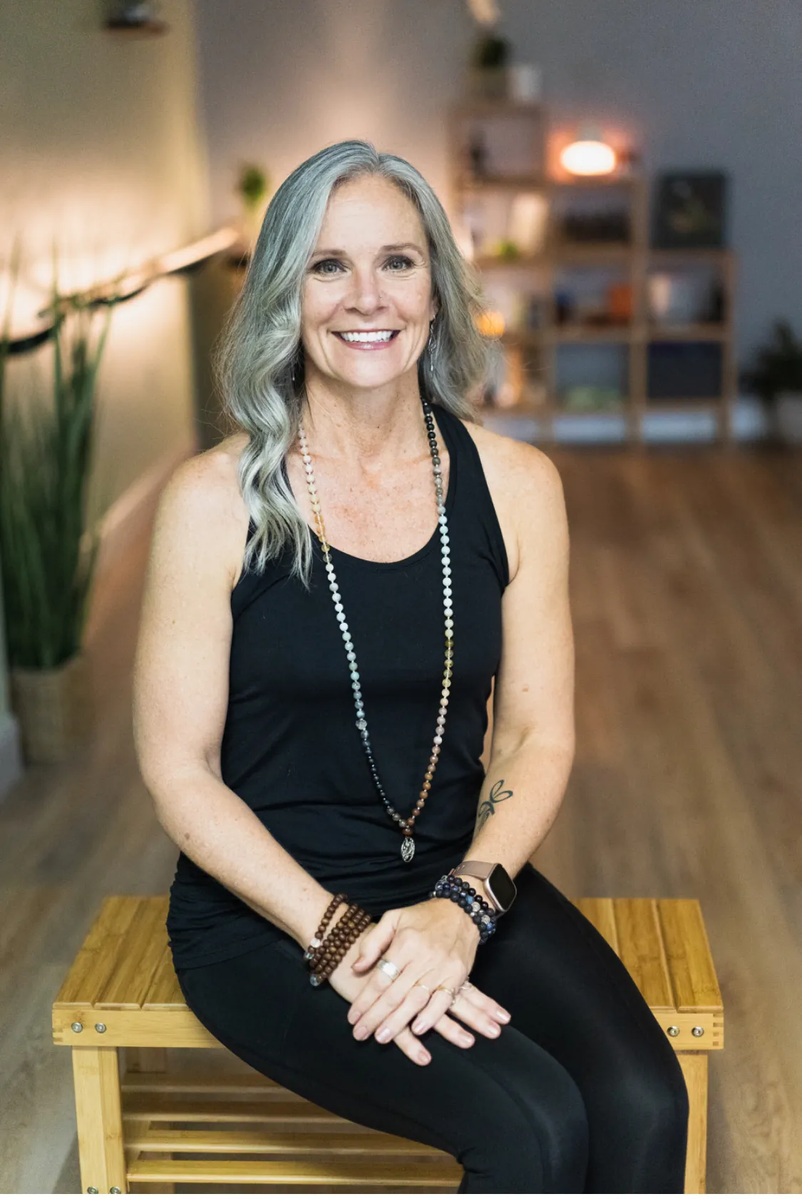 Jill Belongia, owner of JB Wellness, seated in the studio with lamplight behind her.
