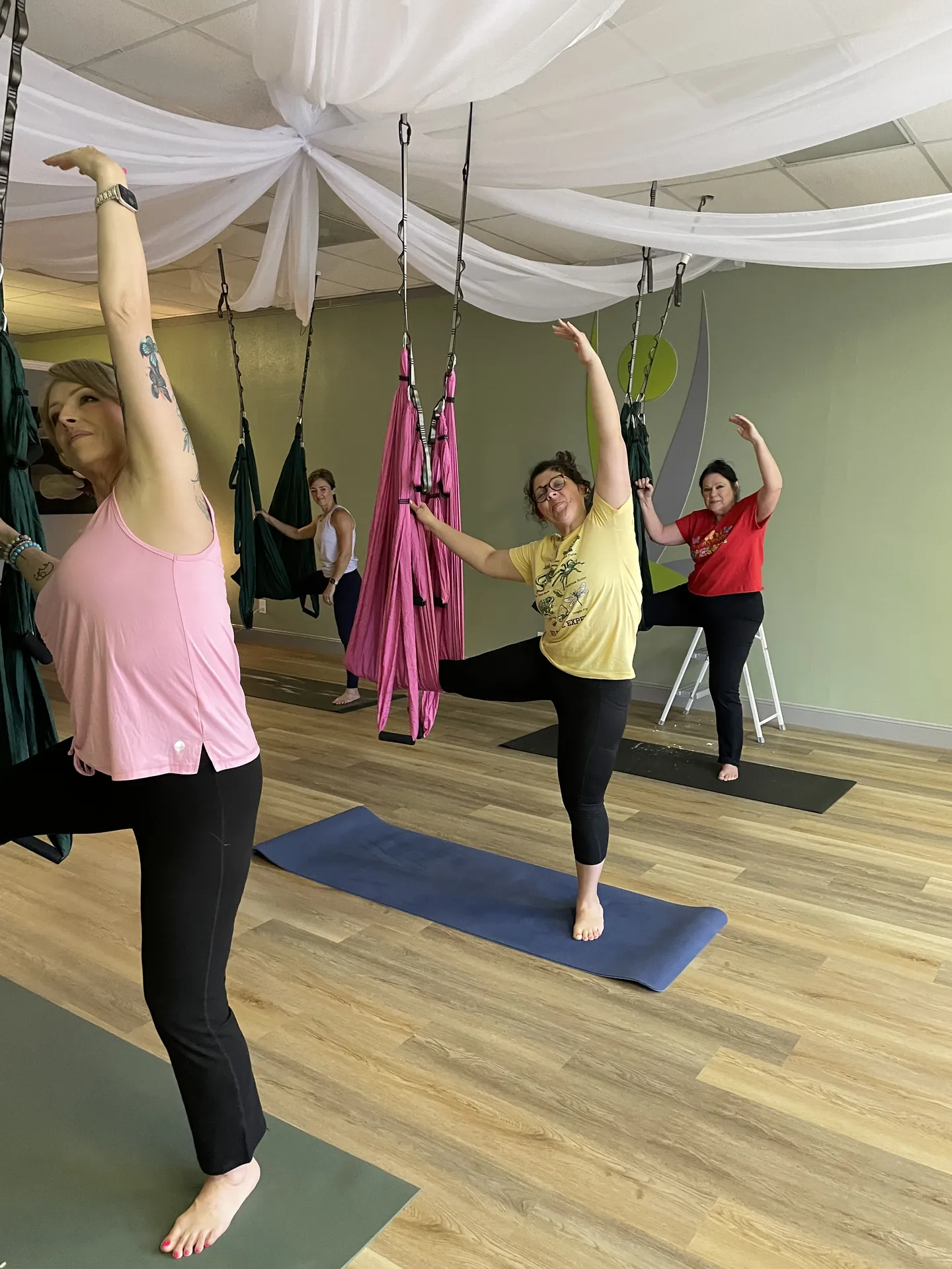 Students in a standing pose with the trapeze hammocks overhead.